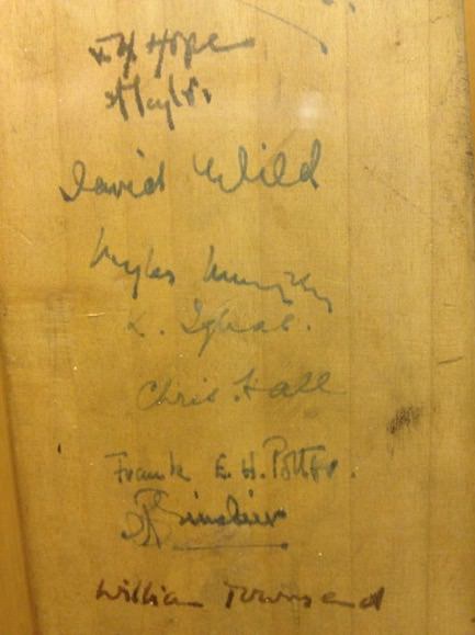 Cricket bat. Detail view of eight signatures in blue or black ink down the length of the bat.